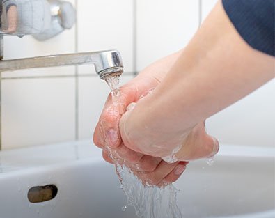 Person wäscht sich die Hände unter Wasser